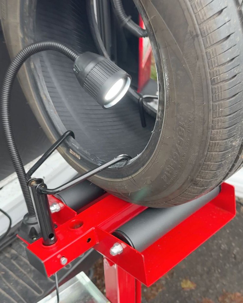 Close-up of a car tire mounted on an inspection stand with a work light inside a mobile tire repair van on the North Shore.